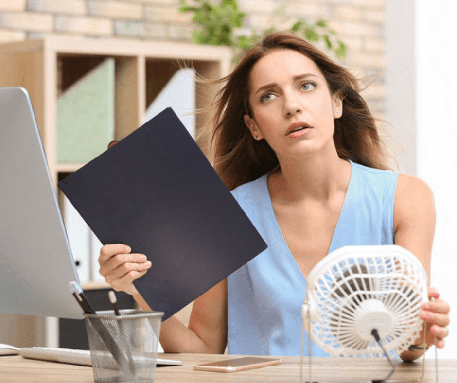 woman using fan and fanning herself because air conditioner is broken